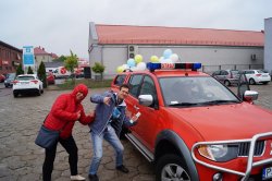 chłopak i dziewczyna pozują na tle samochodu strażaków, samochód ma doczepione kolorowe balony