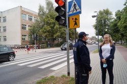 policjant dzielnicowy przy pasach w okolicach szkoły rozmawia z dziewczynką