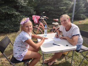 dziecko i kobieta siedzące przy stoliku - osoby wypełniające dokumenty potrzebne do znakowania rowerów
