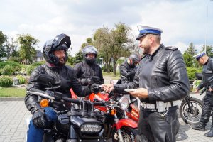 policjant rozdaje ulotki motocyklistom